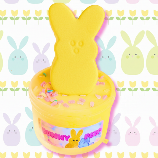 A container of yellow slime with a clay bunny 'peep' on top, displayed on a background pattern with multiple cartoon bunny faces.